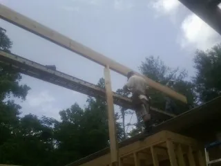 Carpenter setting a ridge beam over a new addition frame — Ice Dam Removal by Roofing Brothers in Social Circle