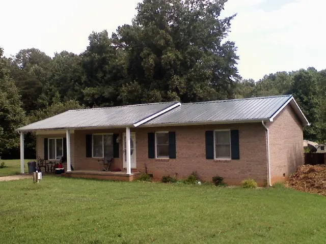 Gray metal roof on a brick ranch house with a side carport in Social Circle