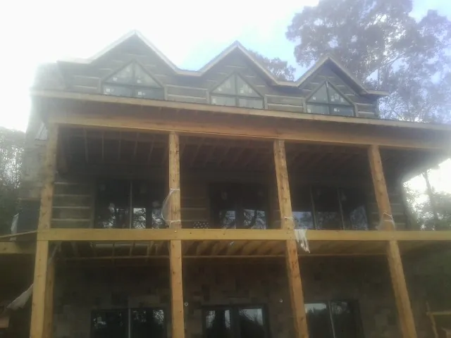 Dormers and porch framing on a large log home under construction — Roof Coating work by our crew in Social Circle