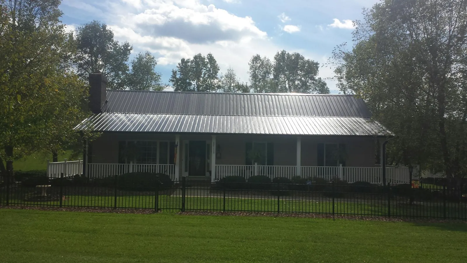 Gray metal roof on a brick ranch with a full width front porch — Gutter Guard Installation work by our crew in Social Circle