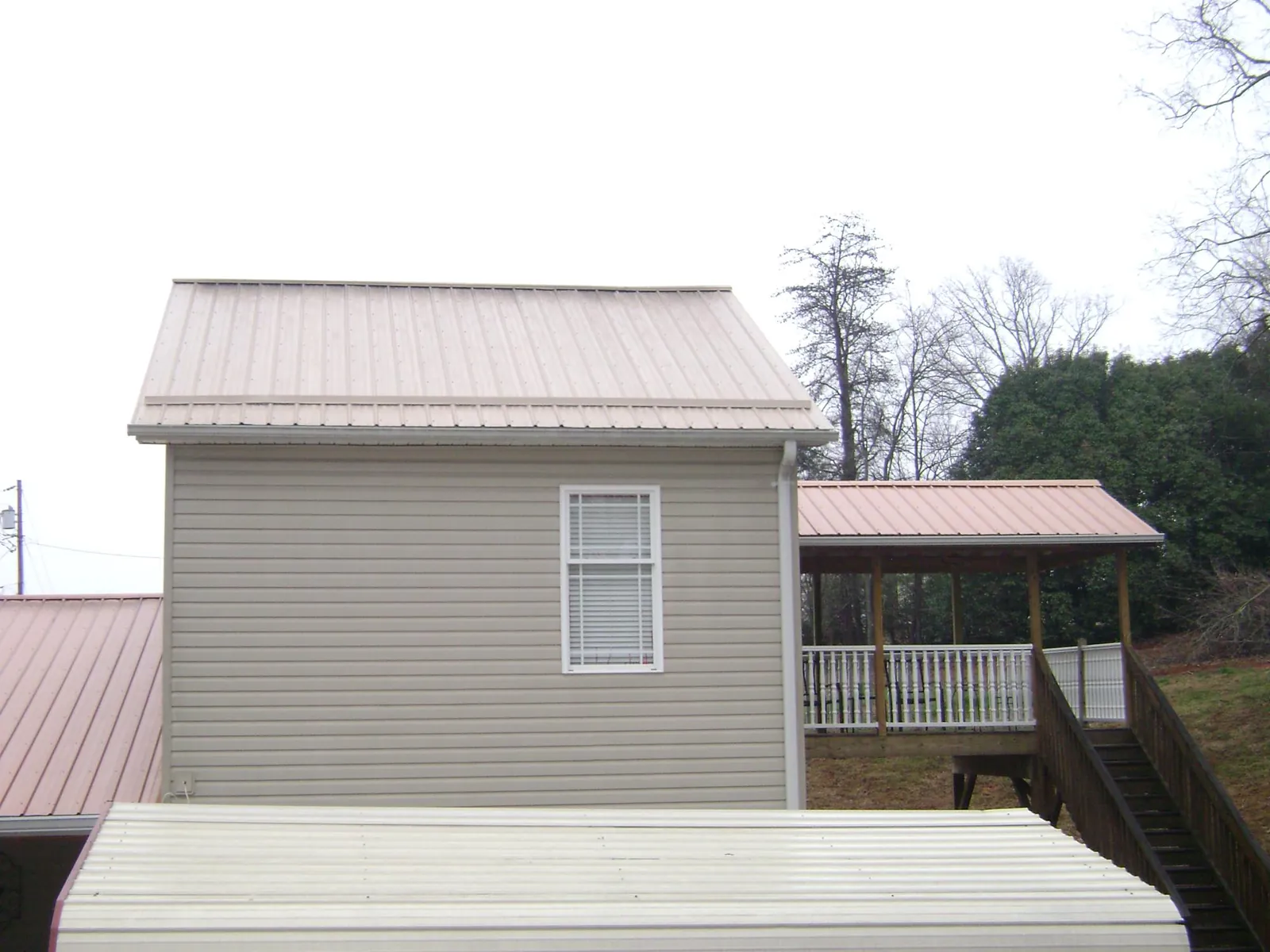 Tan metal roofs on a two story addition and attached porch, from a Roof Replacement job in Social Circle