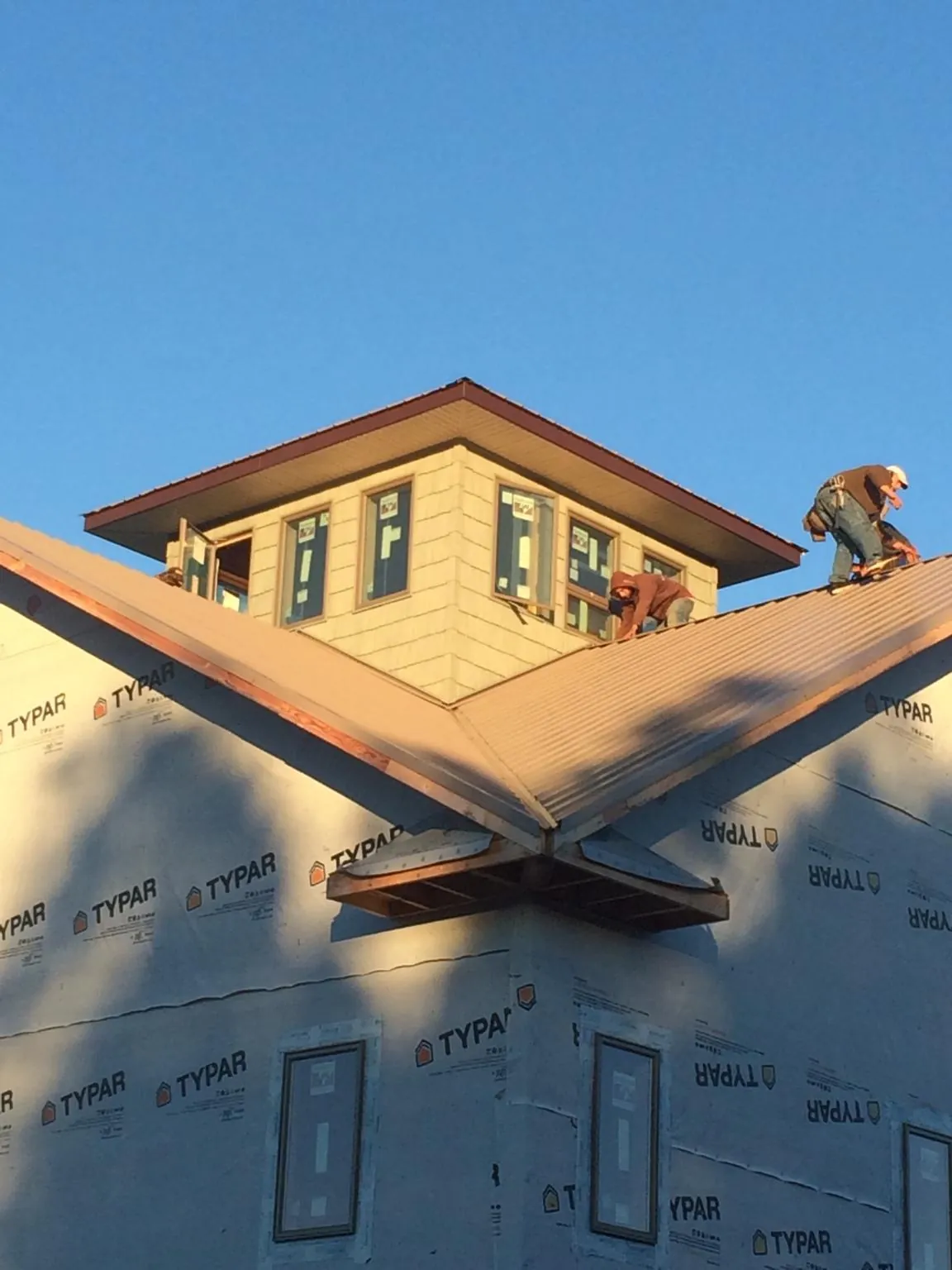 Roofers working around a rooftop cupola on a new metal roof at sunset — Roof Waterproofing in Social Circle by Roofing Brothers